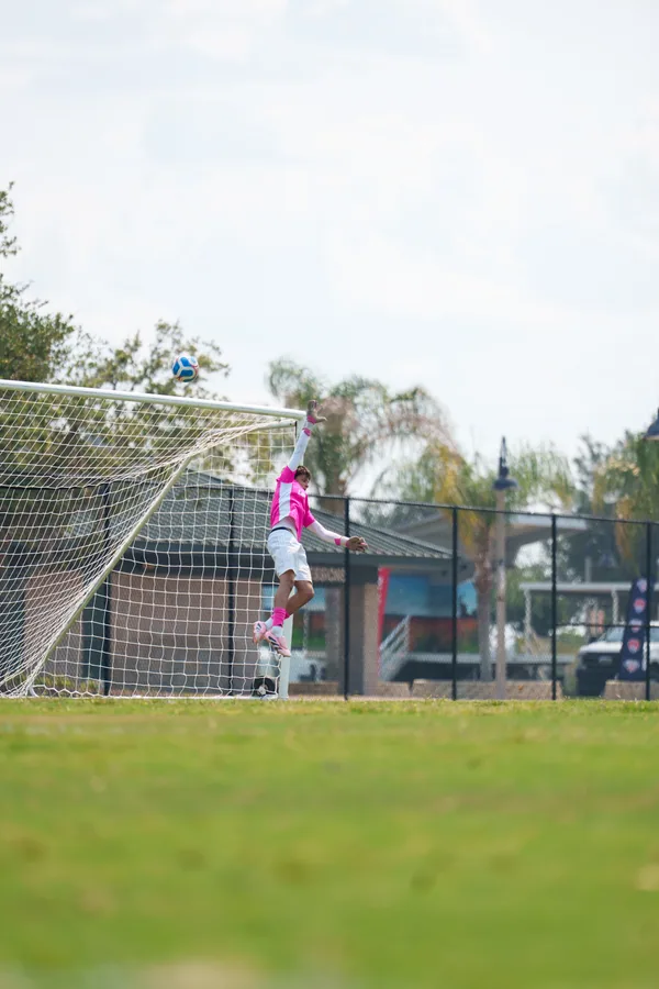 Gavin reaching upward toward a ball above the goal